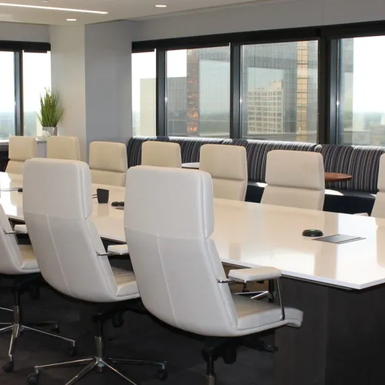 A boardroom with white chairs arranged around a wide table
