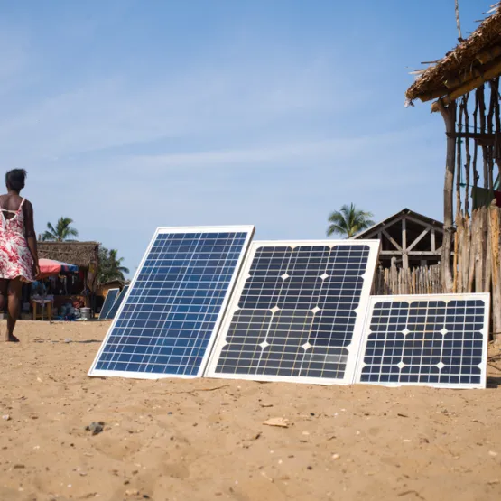 Solar panels installed in a rural location. There's a woman walking in the background