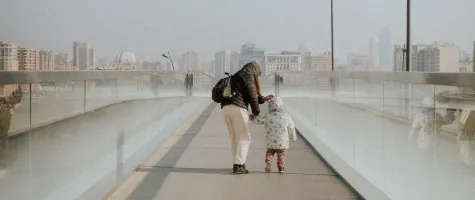 A woman and a todler walking over a bridge