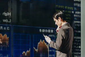 man-checks-stockmarket-stocks-phone-asia-mirrored-scaled