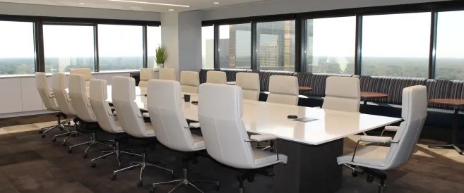 A boardroom with white chairs arranged around a wide table
