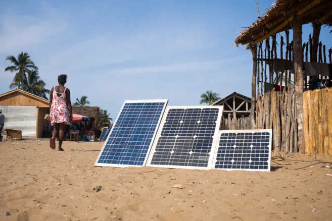 Solar panels installed in a rural location. There's a woman walking in the background